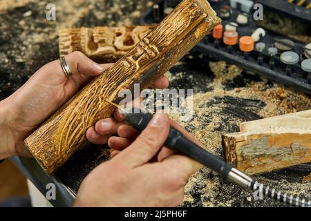 Close up male hands using power wood working tools graver, carving Stock Photo
