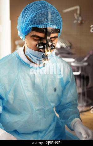 Dentist in binoculars, use of binoculars in dental treatment, dentist in the office, magnifying glass for binoculars. Stock Photo