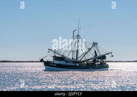 A commercial shrimp boat heads out to see through the Brownsville Ship Channel by South Padre Island, Texas. Stock Photo