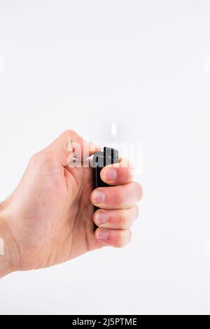 a gas lighter in hand burns fire on a white background Stock Photo