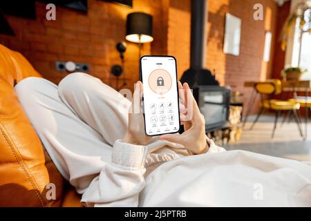 Woman using phone with running smart home security application Stock Photo