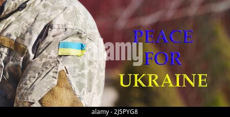 Ukrainian flag with copy space and text - Peace for Ukraine. Ukrainian flag on military uniform. Stop Russian aggression. Stop the war in Ukraine. Stay with Ukraine. Sensation. Pray for Ukraine