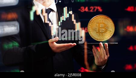 Smartphone with Bitcoin trading chart . Holding in hand a gold Bitcoin Cash coin. Trading on the cryptocurrency exchange. Stock Photo