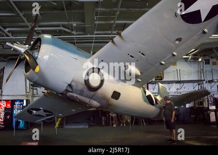 Fighter F4F Wildcat plane contemplated by a visitor at the USS Midway aircraft carrier hangar deck, San Diego Navy Pier Stock Photo