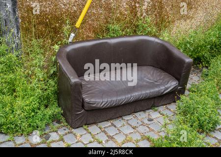 Fly-tipped sofa in back street Stock Photo
