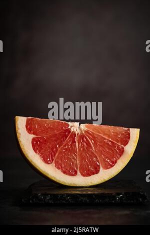 a piece of grapefruit on a dark background Stock Photo