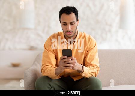 Young man using smart phone at home Stock Photo