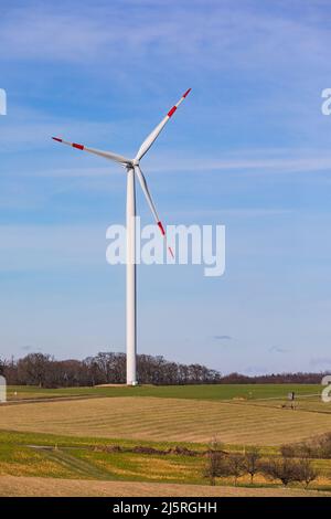 A red and white wind turbine on a mountain against a blue sky Stock Photo