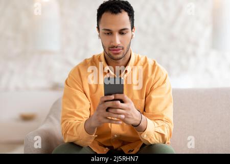 Young Arab man using cellphone wearing headphones Stock Photo