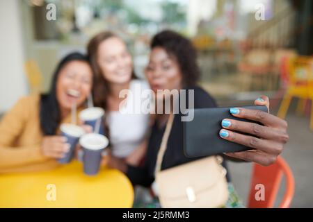 Woman with bright blue nail polish taking selfie with best friends in cafe, selective focus Stock Photo