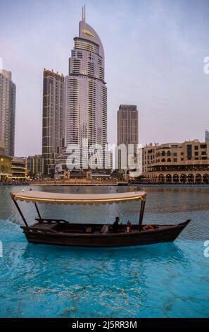 view of the Dubai mall and the Dubai Fountain captured in the evening with a typical boat in the foreground. The Dubai Mall is the largest mall in the Stock Photo