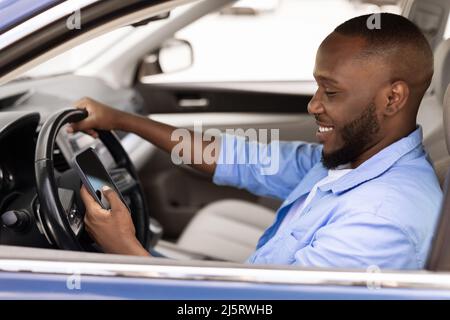 Happy black man using showing smartphone driving car Stock Photo