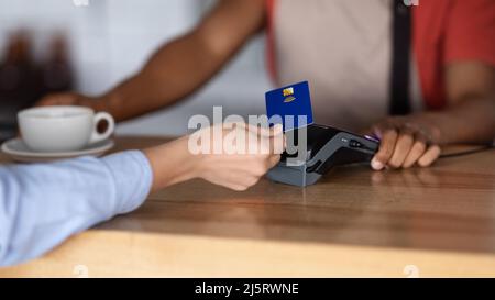 Millennial african american guy waiter in apron gives coffee to customer Stock Photo