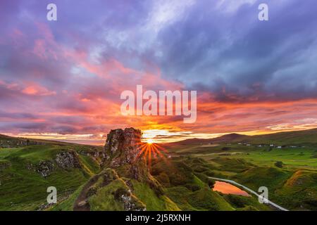 Cloudy skies with sunset on the Isle of Skye. yellow orange red sky with clouds. Landscape with rocks Castle Ewen in summer. Sandy path to the rock Stock Photo