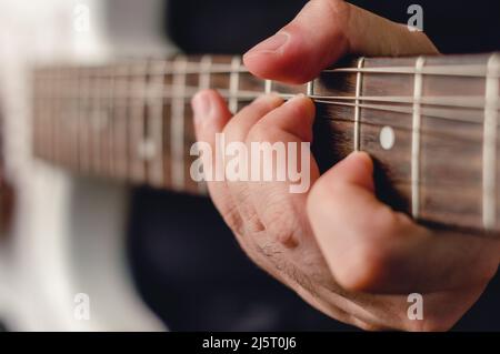 close-up male hand doing bending technique on electric guitar, focus on left hand. Stock Photo