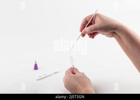 ATK SARS Cov 2 coronavirus rapid antigen test nasal kit. A woman doing a self-test for Covid-19 at home. Hand holding test on white background. Covid- Stock Photo