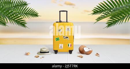 Suitcase with travel stickers on beach surrounded by hat, coconuts, shells and palm leaves. Travel concept Stock Photo