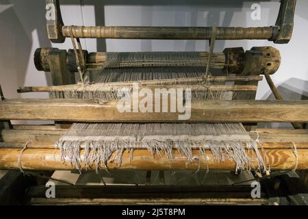 The machine is a hand-made wooden loom with threads for working on the machine. An old loom Stock Photo
