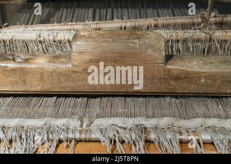 The machine is a hand-made wooden loom with threads for working on the machine. An old loom Stock Photo