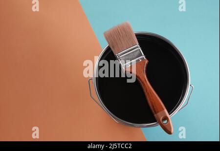 Top view of paintbrush on paint can on blue and orange background Stock Photo