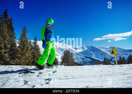 Boy on snowboard in helmet and mask stand over mountains Stock Photo