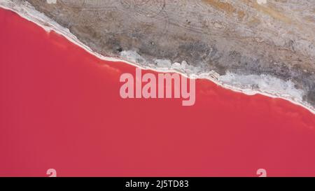 Flying over a pink salt lake. Salt production facilities saline evaporation pond fields in the salty lake. Dunaliella salina impart a red, pink water Stock Photo