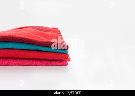 Stack of folded clothes, clean red cotton textile t-shirts on white background with copy space. Laundry, washing, ironing concept. Stock Photo
