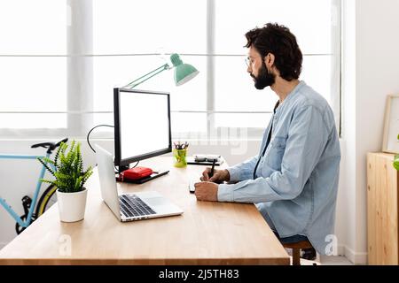 Professional young creative designer using graphic tablet and laptop computer Stock Photo