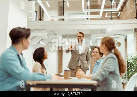Leader standing in office and explaining new ideas to colleagues Stock Photo