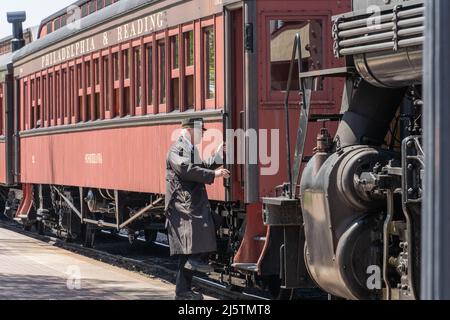 Strasburg, PA, USA - April 20,2022:  Train Conductor steps onto vintage train at the Strasburg Railroad station Stock Photo