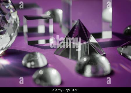 Crystal prism refracting light, magic crystals and pyramid, sphere and cube on purple background. Spiritual healing crystal practice. Feng Shui, good Stock Photo