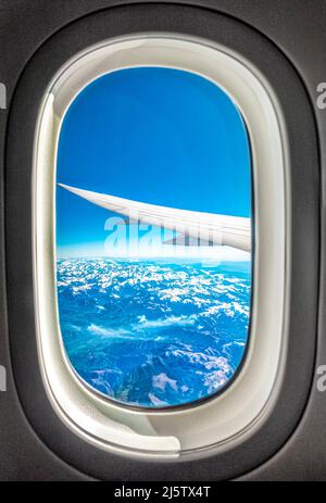 Looking out of plane window flying over snow capped Pyrenees mountains. View from a airplane window. Pyrenees snowcapped from aeroplane window. Stock Photo