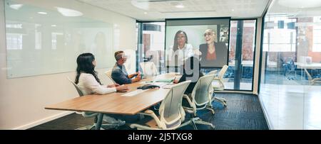 Modern businesspeople having a video conference in a boardroom. Group of creative colleagues attending a virtual briefing with their partners. Global Stock Photo