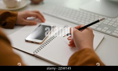 Close-up hands, Female college student doing her homework at her desk, writing on school notebook. Stock Photo