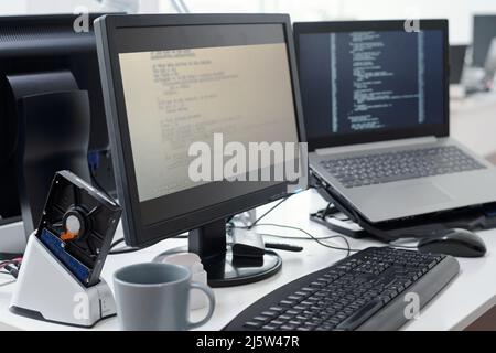 Computer monitor with decoded data on screen and laptop of contemporary programmers in openspace office or bureau Stock Photo