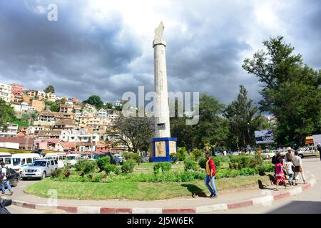 cars and people on MDRM square - the stone pillar with a Madagascar map marks the uprising of 1947. Antananarivo, Madagascar. Stock Photo