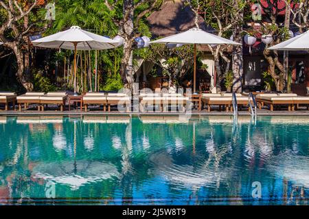 Swimming pool with relaxing beds and sun umbrella in tropical garden in island Bali, Indonesia Stock Photo