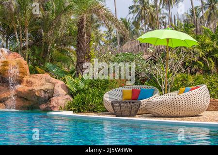 Swimming pool with relaxing beds and sun umbrella in tropical garden in Thailand Stock Photo