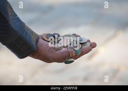 Indian man holding antique coins in his hands for sell for tourists, close up, India Stock Photo
