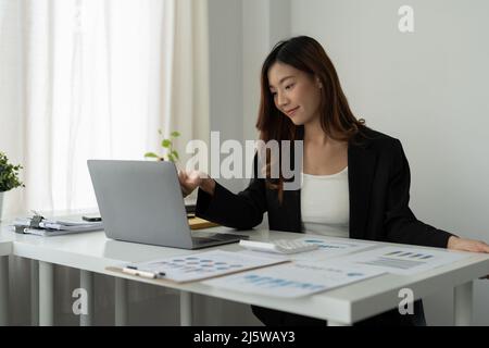 Asian accountant or financial expert analyze business report graph and finance chart at corporate office. Concept of finance economy, banking business Stock Photo