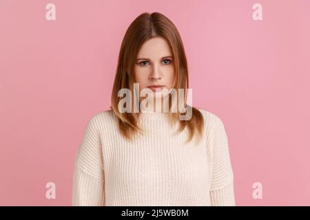Portrait of blond woman looking at camera with gloomy grimace, feeling annoyed and dissatisfied with defeat, negative emotions, wearing white sweater. Indoor studio shot isolated on pink background. Stock Photo