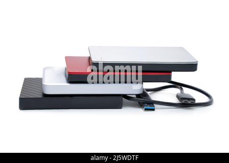 Selection of various compact 2.5 inch hard disk drives with a connection cable isolated on white background. Stock Photo