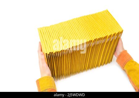 Crop view of female hands stacking yellow padded envelopes on a white table background. Stock Photo