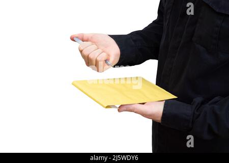 Man in black uniform using a retractable ballpoint pen to sign a yellow shipping envelope, copy space. Stock Photo
