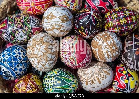 Many bright and colorful easter eggs in a wicker basket, close up. They are hand-painted or dyed Stock Photo