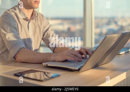 Male hands typing, using laptop in office. Designer working at workplace. Stock Photo