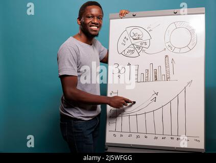 Office assistant doing project presentation with charts and financial statistics on white board over blue background. Consultant manager using business placard for advertisement. Stock Photo