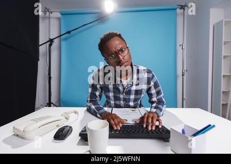 Behind the scenes of suspicious doubtful marketing department team leader looking confused at wrong infographics. Unsure young adult person using work computer to finish report. Stock Photo