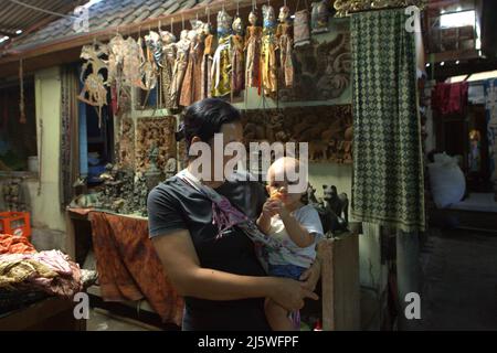 Ni Wayan Sudiati, a traditional clothing artist, babysitting at her workshop in the traditional village of Tenganan Pegringsingan in Karangasem, Bali, Indonesia. Stock Photo