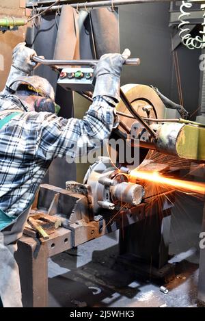 workers in safety clothing sanding a casting in an industrial company Stock Photo